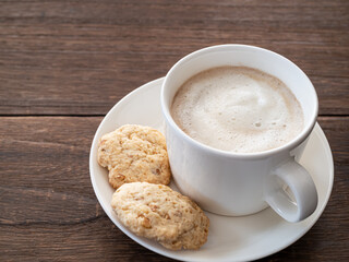 カップに入ったカフェオレとソーサーの上のナッツクッキー