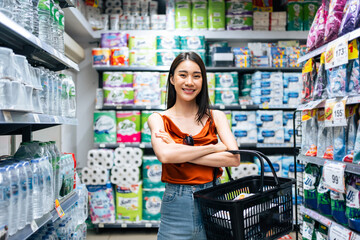Portrait of Asian young woman hold grocery basket walk in supermarket. 