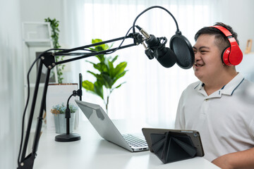 Young trendy DJ man wearing headphone and speak on microphone at studio.