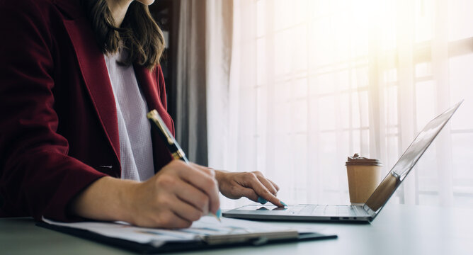 Attractive smiling young asian business woman work at home office, Asian woman working on laptop computer holding tablet.
