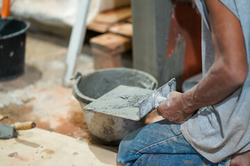 Closeup hands of builder holding mortar pan for plastering walls with cement in construction site