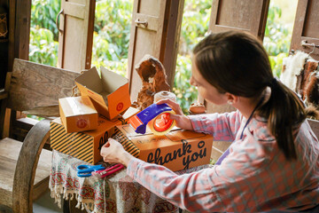 Closeup female seller packing products to deliver parcels to customers., Online sale concept.