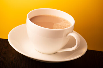 Cup of milk tea on yellow background
