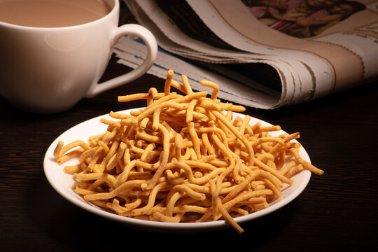Besan sev namkeen served with cup of tea and newspaper