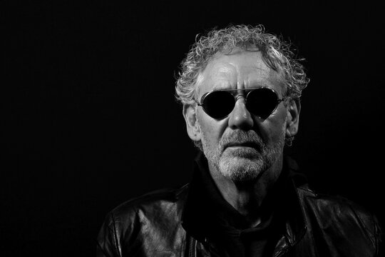 Black And White Portrait Of An Attractive Older Caucasian Man With Dark Sunglasses.