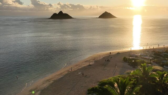 reveal shot birds eye view aerial drone of lanikai beach and mokulua islands in lanikai hawaii at sunrise beautiful clear beach water palm trees canoes reef paradise oceanfront property