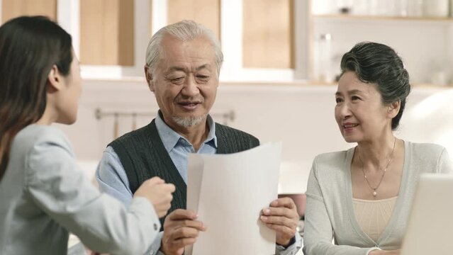 happy senior asian couple sitting with financial consultant making retirement plan