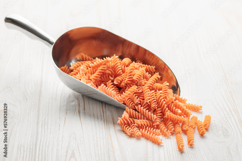 Wall mural Fusilli red lentil pasta on a wooden background.