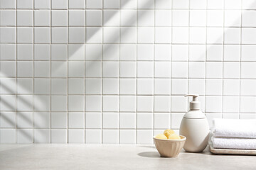 Various objects on a white tile background with warm sunlight shining through
