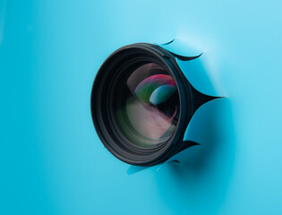 Hidden camera lens through hole in blue paper,Concept of paparazzi or hidden camera