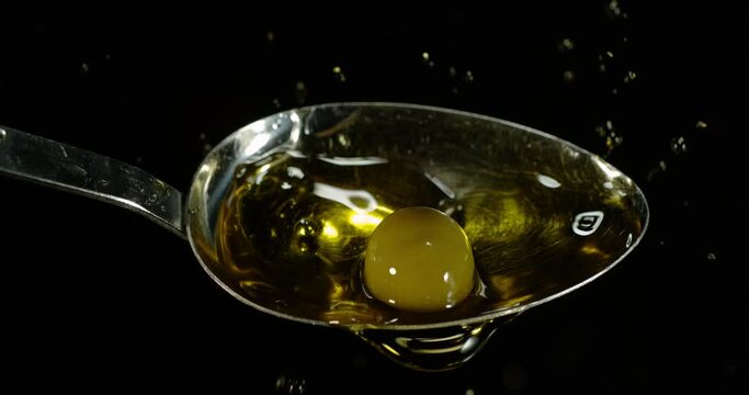 Green Olive, Olea europaea, Falling in a Spoon against Black Background, Slow Motion 4K
