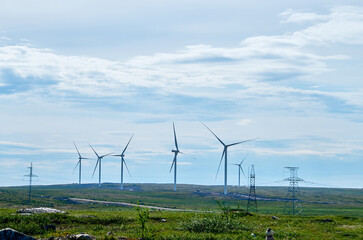Wind farm in hilly area under cloudy sky