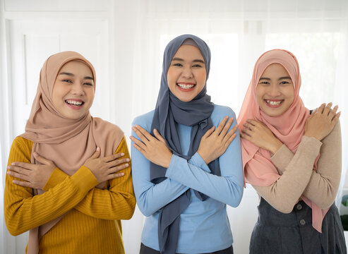 Embrace equity on multiracial Internal Women's Day. Group asian muslim lady good mood hands hug herself shoulders enjoy joyful warmth toothy smile.