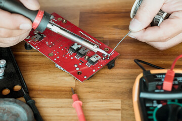 technician man holding iron solder and repairing the circuit board by soldering. electrical work...