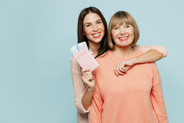 Elder parent mom young adult daughter two women wear casual clothes hold passport ticket hug isolated on plain blue background Tourist travel abroad in free time rest getaway. Air flight trip concept.
