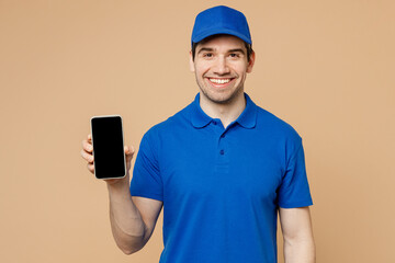 Delivery guy employee man wears blue cap t-shirt uniform workwear work as dealer courier hold in hand use mobile cell phone with blank screen workspace area isolated on plain light beige background.