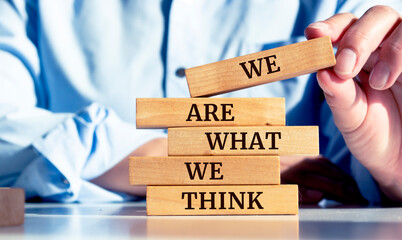 Close up on businessman holding a wooden block with "We Are What We Think" message