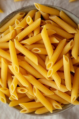 Raw Organic Penne Pasta in a Bowl on a gray background, top view. Flat lay, overhead, from above.