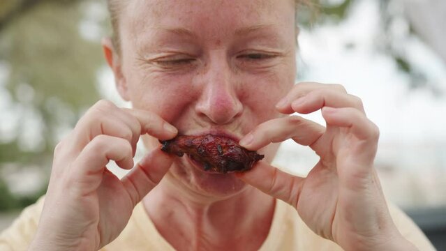 Woman eating fried chicken wing.
