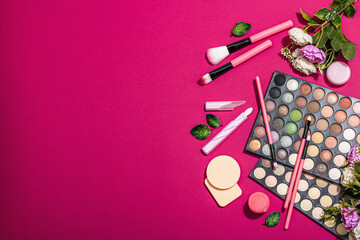 Make up set with colorful eyeshadow palettes, brushes, sponges and flowers. Viva magenta background
