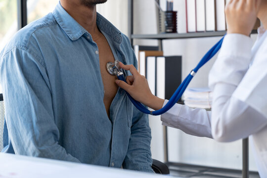 An Asian female doctor uses a stethoscope to listen to the heartbeat of a male patient for guidance in treatment and preventive care. health check concept.