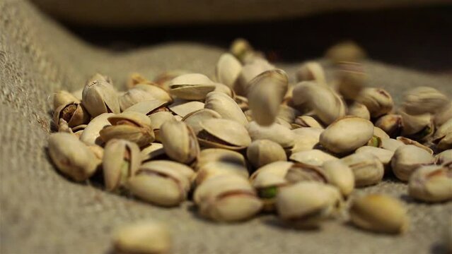 salted pistachios falling from above on a linen burlap background