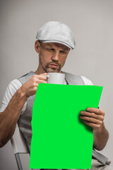 Handsome man with cup of coffee reading newspaper while sitting on chair, copyspace
