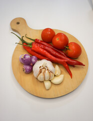 Garlic, Chili, red onion and tomatoes on a wooden plate, close up shot.