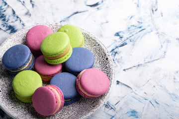 Plate with multi-colored macaroons close-up view from above