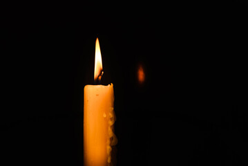 One light candle burning brightly in the dark background.Copy space.