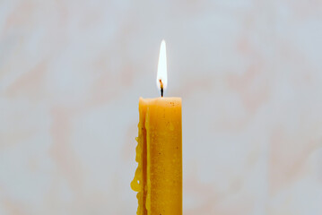 Candle light for spirituality ceremony against grey blurred background.Hot wax drips from the...