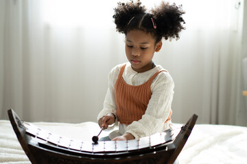 A little girl plays the xylophone in a music class. The child learns to play the xylophone