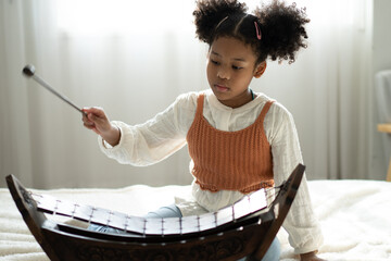 A little girl plays the xylophone in a music class. The child learns to play the xylophone
