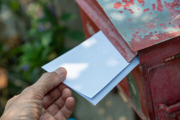 Hand inserts letter into red post box