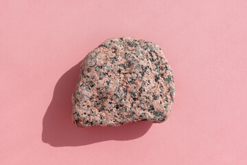 Abstract empty podium made of multicolored stone on a pink background. Showcase for product promotion, beauty, natural eco cosmetic. Top view.