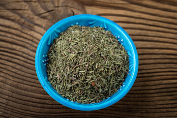 Dried thyme in a bowl on a wooden background