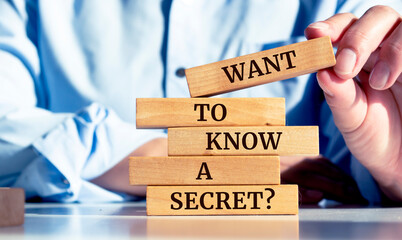 Close up on businessman holding a wooden block with "Want To Know A Secret?" message