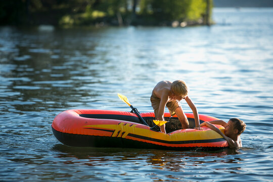 Two Boys swimming and playing on an inflatable raft in Duck Bay on Payette Lake in McCall, Idaho