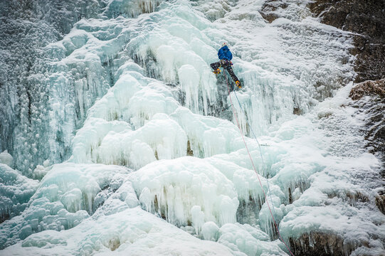 Man lead climbing an ice fall in the middle of a snow storm in ArgentiÃ¨re, Chamonix, France.