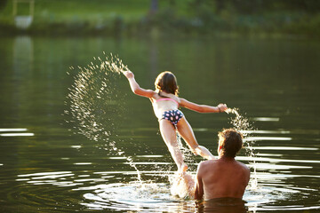 A father and daughter playing in a lake.