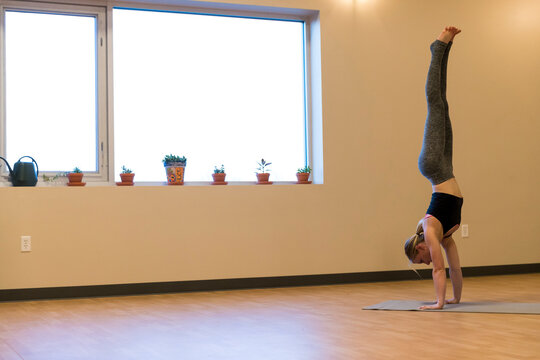 Young fit woman in handstand yoga pose