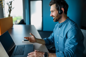 Bearded man sitting at the laptop and having a video call