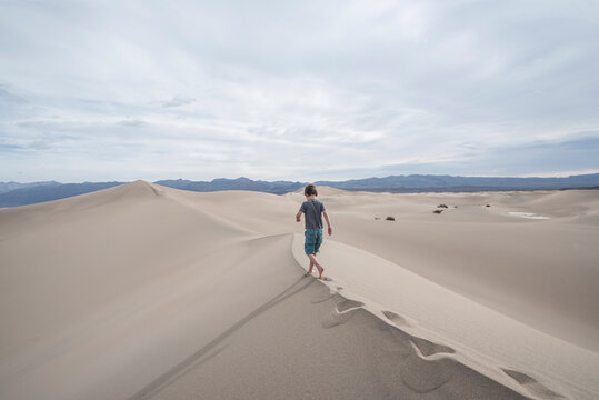Boy walking alone on Mesquite Flat Sand Dunes in Death Valley National Park, California, USA