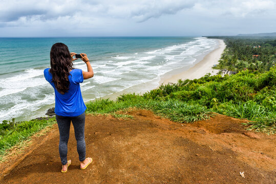 Woman taking picture of beach, Itacare, South Bahia, Brazil