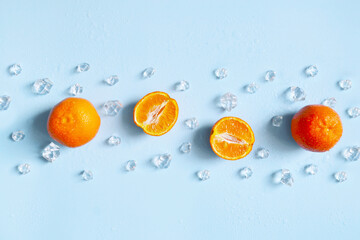 Frame, lay out ice cubes, mandarin and water drops on the blue background. Summer vibes. Cooling fresh humid template composition. Empty space for text on the top. Flyer, card, invitation.