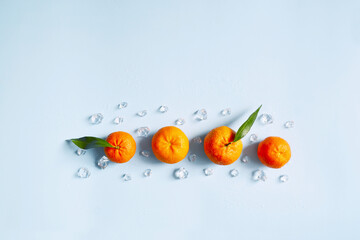 Frame, lay out ice cubes, mandarin and water drops on the blue background. Summer vibes. Cooling fresh humid template composition. Empty space for text on the top. Flyer, card, invitation.