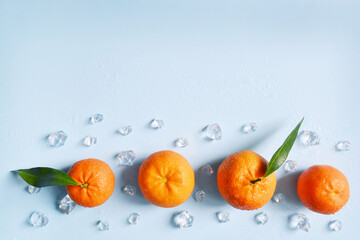Frame, lay out ice cubes, mandarin and water drops on the blue background. Summer vibes. Cooling fresh humid template composition. Empty space for text on the top. Flyer, card, invitation.