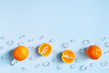 Frame, lay out ice cubes, mandarin and water drops on the blue background. Summer vibes. Cooling...