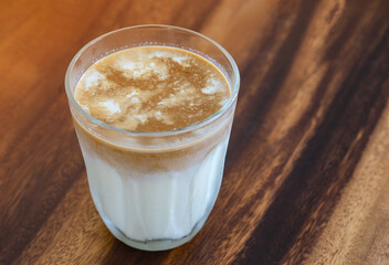 Dirty coffee in transparent glass on brown wooden table with copy space