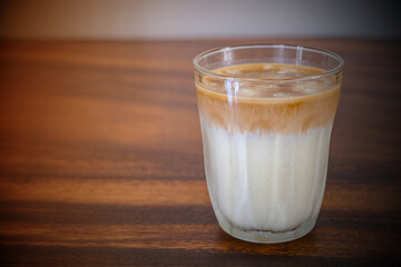 Dirty coffee in transparent glass on brown wooden table with copy space